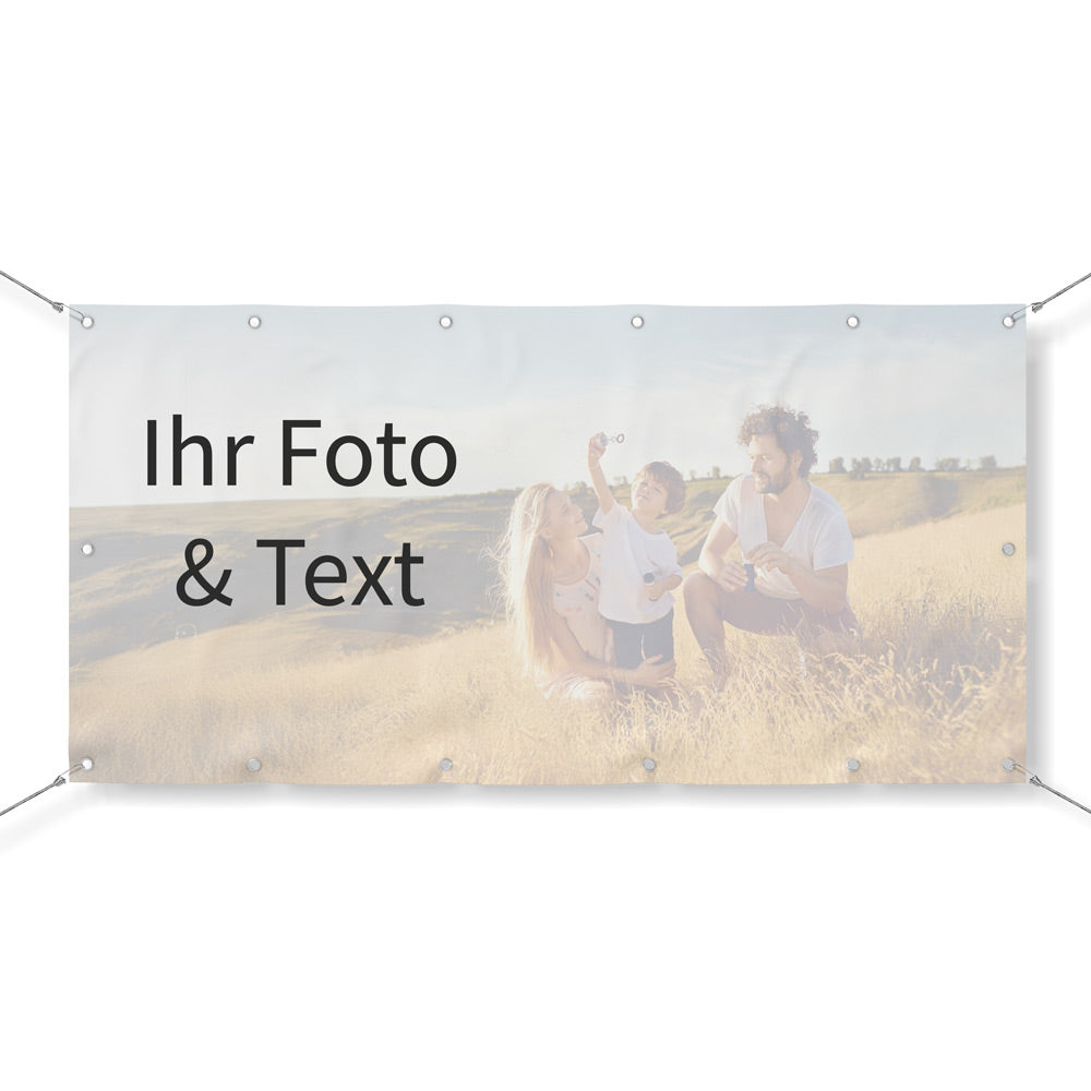 Vorschau eines personalisierbaren Werbebanners mit eigenem Foto und Text. Das Beispielmotiv zeigt eine Familie auf einer Wiese. Das Banner ist mit Ösen an den Ecken versehen und gespannt, ideal für den Außen- oder Innenbereich. Perfekt für Werbung, Veranstaltungen oder individuelle Dekoration.